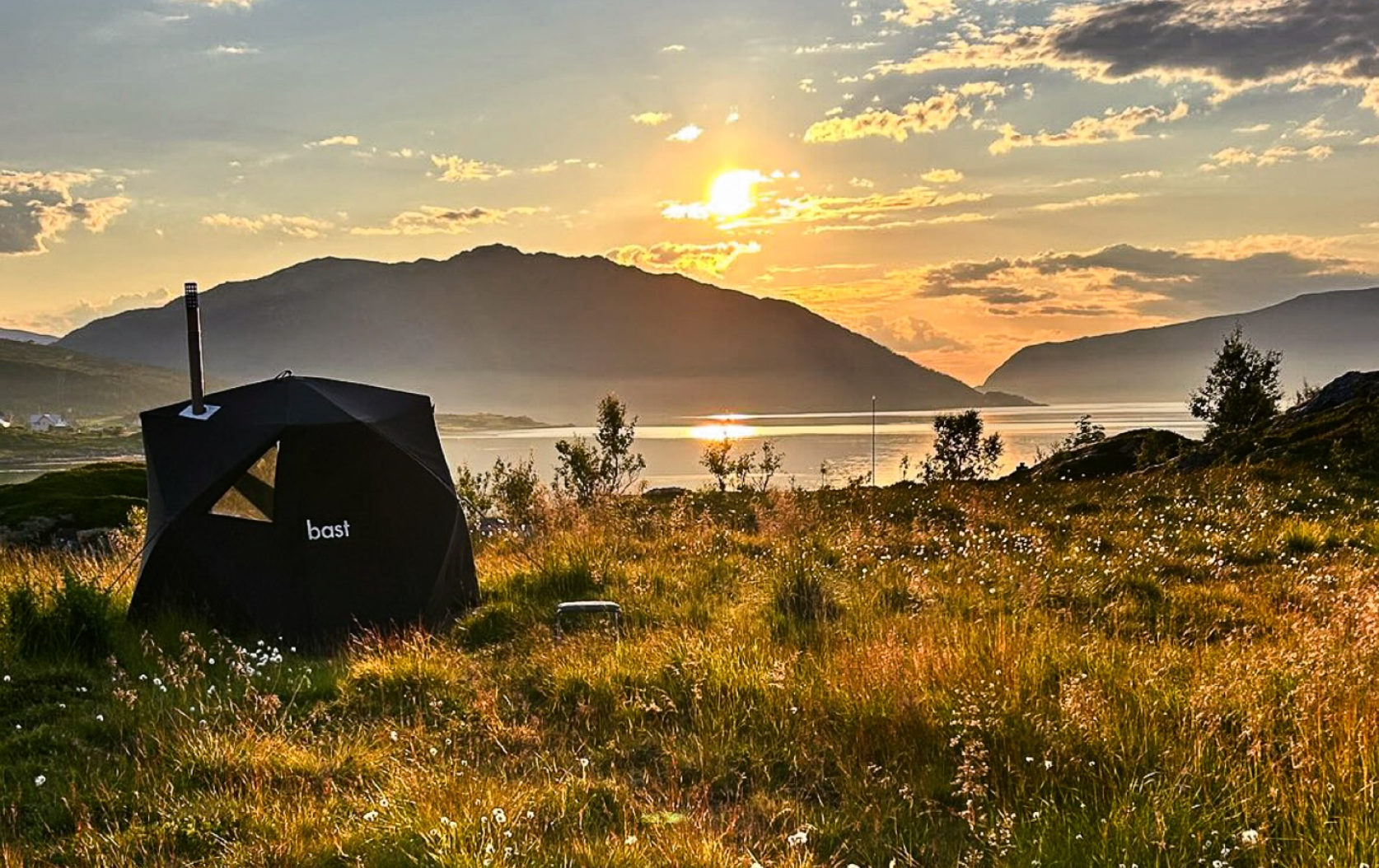 Camping tent with a scenic view of mountains and sunset.