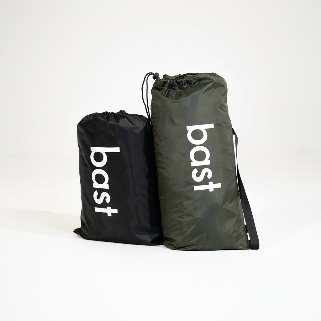 Two drawstring bags, one black and one green, with 'bast' branding on a white background.