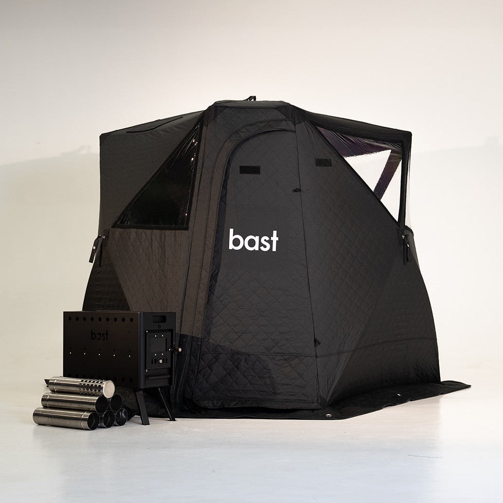black pop-up sauna tent stove and wooden bench with 'bast' branding on a white background