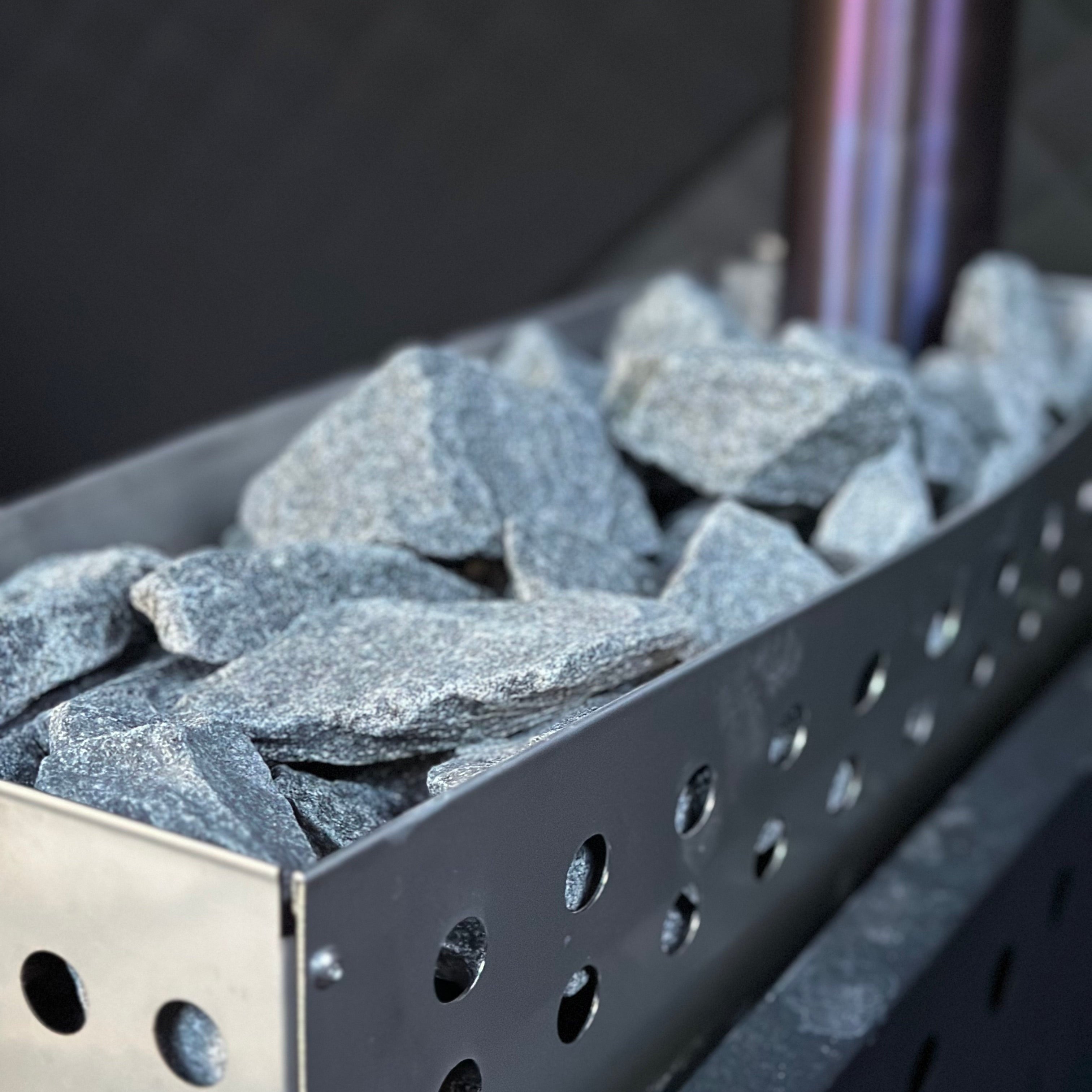 Stainless steel grill filled with sauna stones and a sauna tent in the background