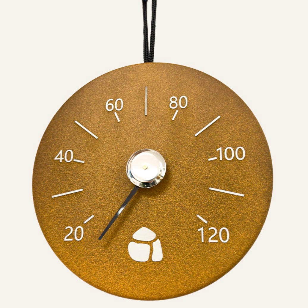 Gold-colored thermometer with white markings on a light gray background