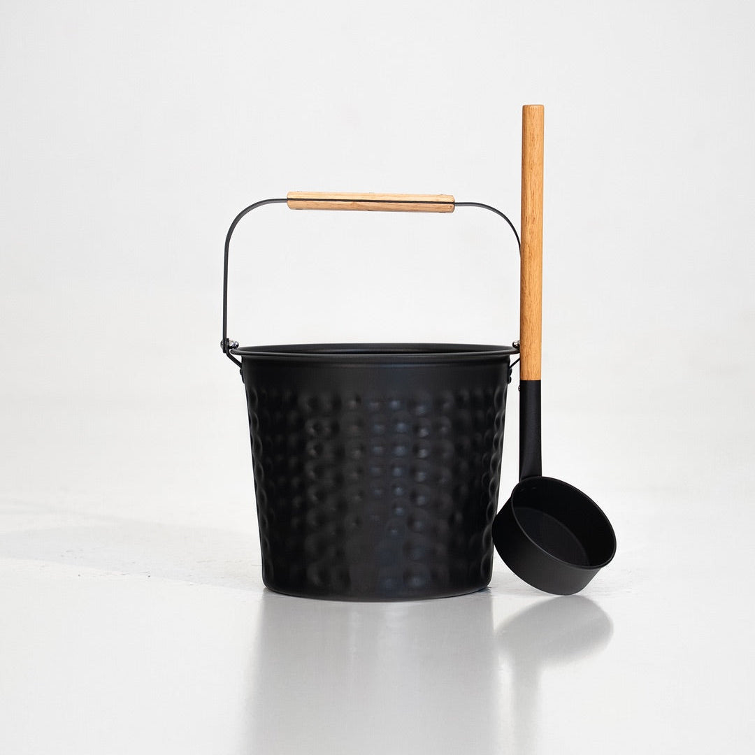 Black metal bucket with wooden handle and ladle on a white background