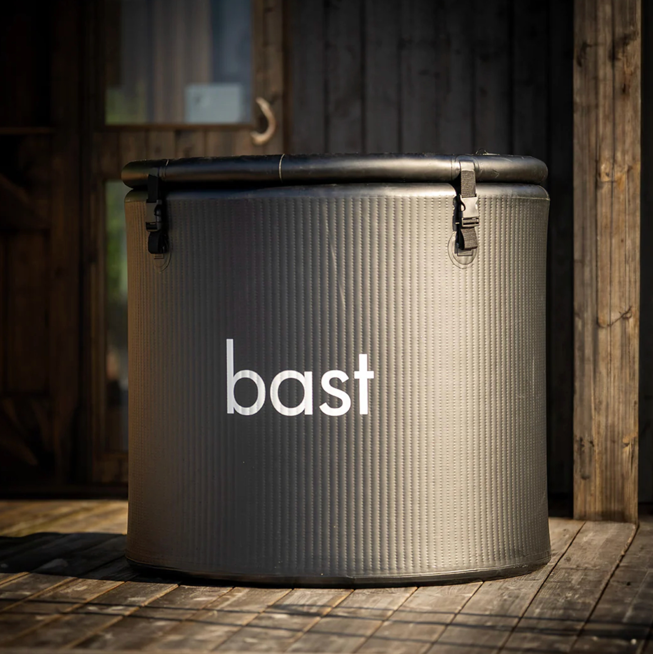 Inflatable ice bath tub with 'bast' branding on a wooden deck.