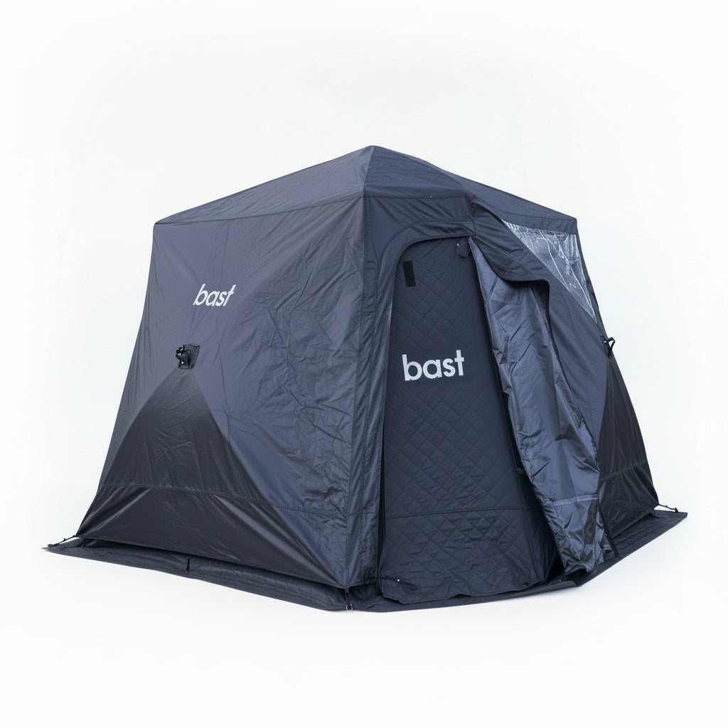 Black outdoor sauna tent with 'bast' branding on a grassy area