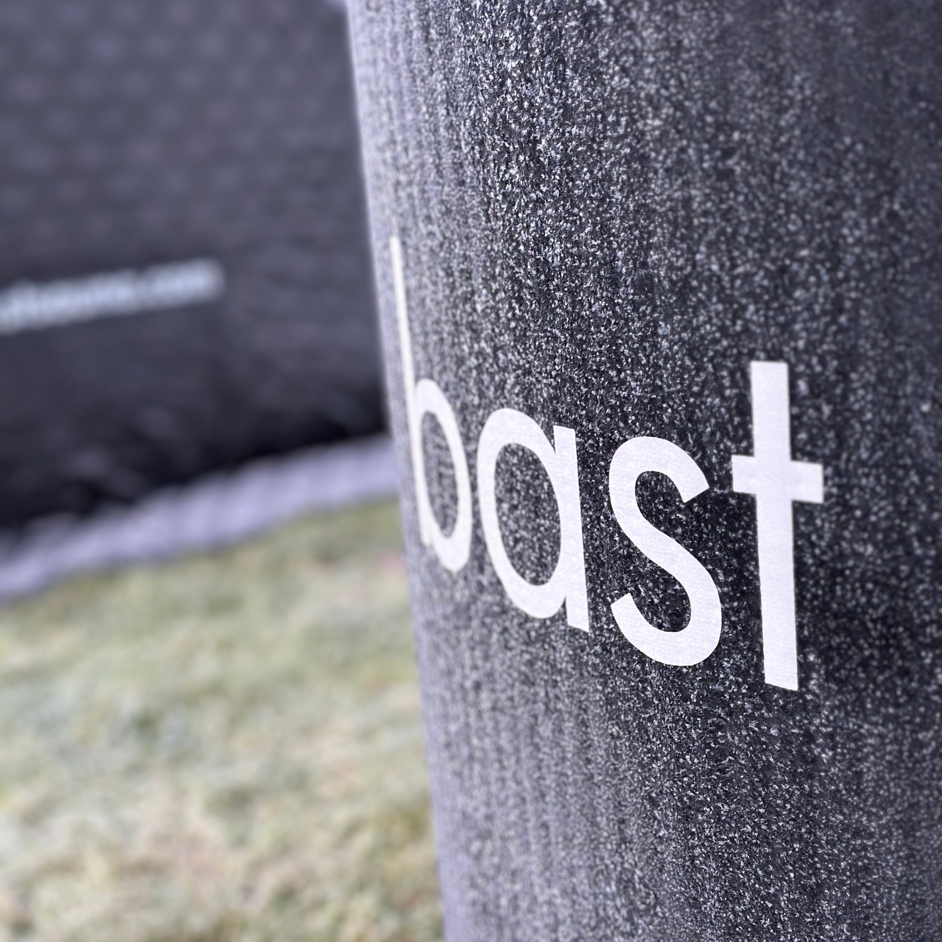 Inflatable ice bath close-up of 'bast' branding on a grassy background with sauna tent in background