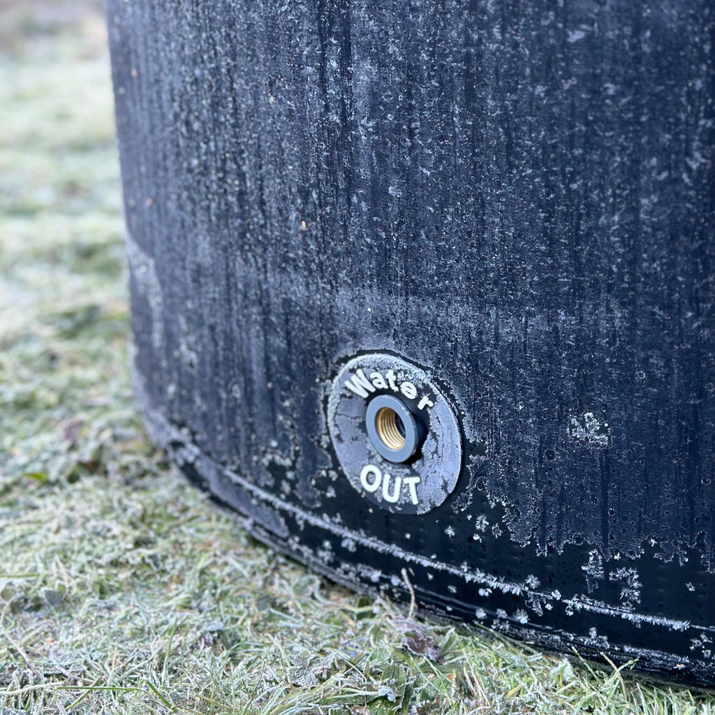 Black metal pipe with a 'Water Out' label on a frosty grass background